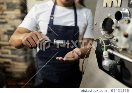 Man showing probe of roasted coffee 63431356
