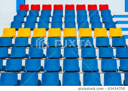 Empty old blue seats in the blue,yellow and red in stadium. Empty old blue seats in the blue,yellow and red in stadium. 63434708