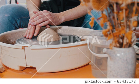 Pottery - the master is putting a piece of clay on the potter's wheel 63435178