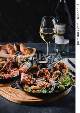 Assorted seafood on plates. Beautiful composition on a served seafood table, squid, shrimp, salmon steak and octopus. Food photo, low key, traditional Italian cuisine. Top view, save the space 63435521