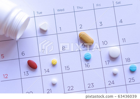 bunch of different pills on a calendar background. bunch of different pills on a calendar background. 63436039