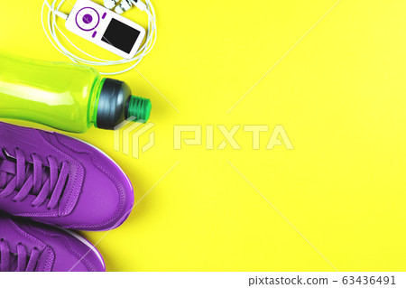 Purple sneakers, bottle, music player and fitness tracker. Concept of sport and healthy lifestyle. Purple sneakers, bottle, music player and fitness tracker. Concept of sport and healthy lifestyle. 63436491
