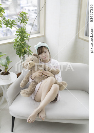 Young woman playing with a teddy bear 63437536