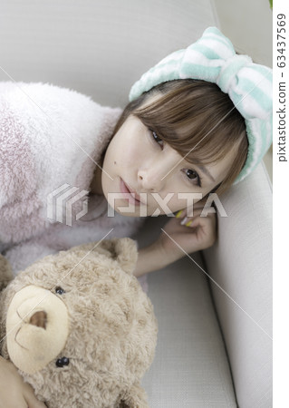 Young woman playing with a teddy bear 63437569