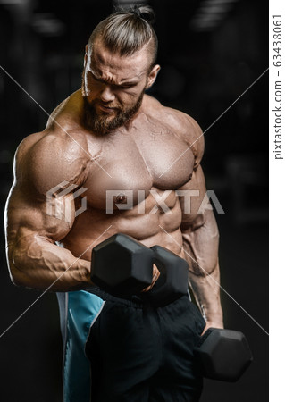 Bodybuilder strong man pumping up biceps muscles Bodybuilder strong man pumping up biceps muscles 63438061