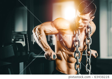 Bodybuilder pumping up chest muscles push-ups bars Bodybuilder pumping up chest muscles push-ups bars 63438228