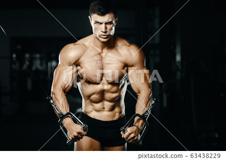 Bodybuilder strong man pumping up biceps muscles 63438229