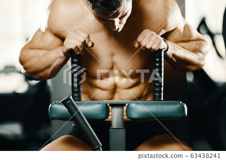 Bodybuilder strong man pumping up abs muscles Bodybuilder strong man pumping up abs muscles 63438241