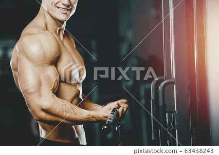 Bodybuilder strong man pumping up biceps muscles 63438243