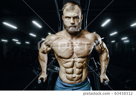 Bodybuilder strong man pumping up abs muscles 63438312