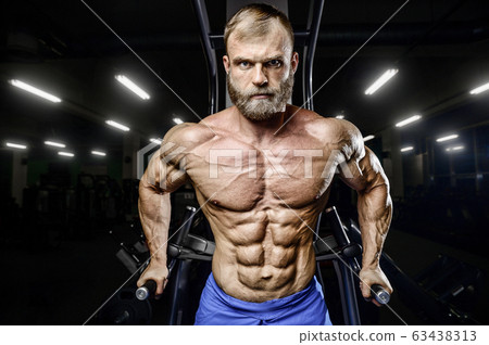 Bodybuilder pumping up chest muscles push-ups bars 63438313