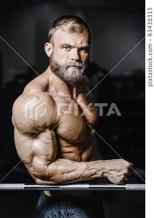 Bodybuilder strong man pumping up biceps muscles 63438315