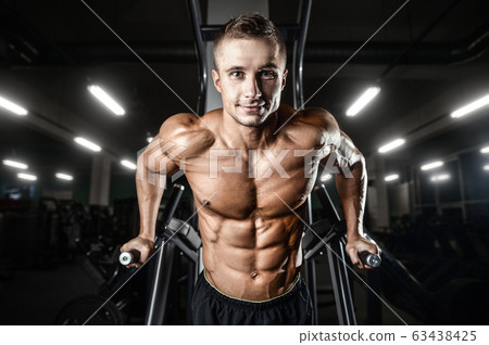 Bodybuilder pumping up chest muscles push-ups bars 63438425