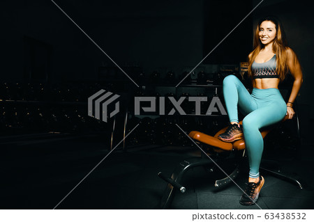 Fitness woman pumping up muscles workout in gym 63438532