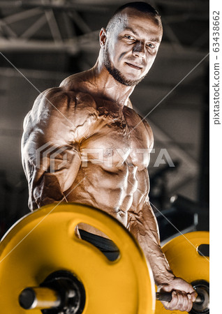 Bodybuilder strong man pumping up biceps muscles 63438662