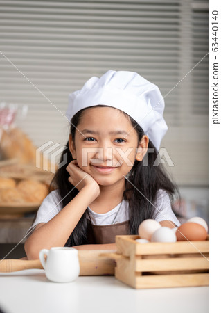 Asian little girl wearing a white chef hat and Asian little girl wearing a white chef hat and 63440140