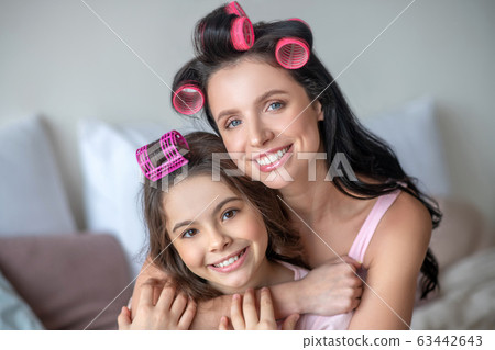 Mom and daughter with hair curlers looking happy 63442643