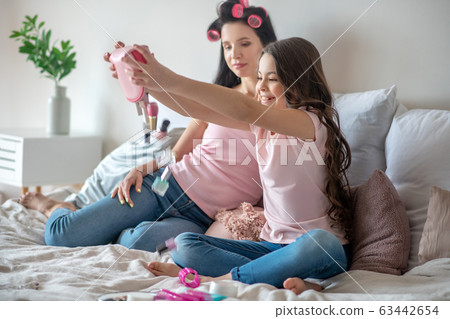 Dark-haired girl in a pink tshirt feeling good playing with cosmetics 63442654
