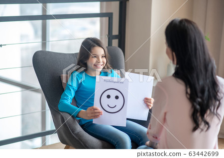 Long-haired teen in a blue shirt holding a table with a happy face 63442699
