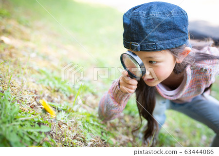 Girl playing with a magnifying glass Girl playing with a magnifying glass 63444086