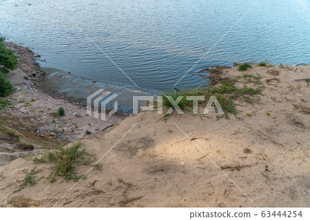 Russia. Saint-Petersburg. Grass and flowers grow on a sandy cliff above the Gulf of Finland in the area of the Fort Krasnaya Gorka  63444254
