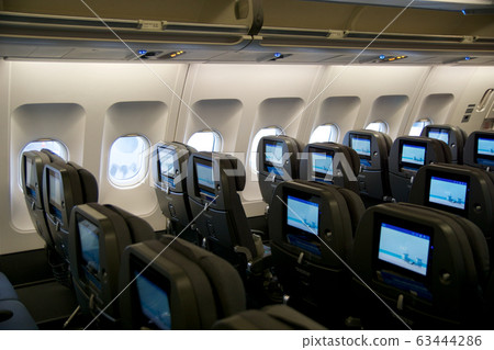 COPENHAGEN, DENMARK - NOV 24th, 2018: Empty airplane seats waiting for passengers and take off in an airplane. Empty plane interior before flight and departure. Watching movie on an aircraft 63444286