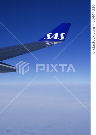 COPENHAGEN, DENMARK - NOV 24th, 2018: Wing of an airplane cruising above the clouds COPENHAGEN, DENMARK - NOV 24th, 2018: Wing of an airplane cruising above the clouds 63444336