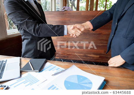 Two business women shaking hands after analysis the chart, set targets for new management success Two business women shaking hands after analysis the chart, set targets for new management success 63445688