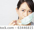 Asian woman was cold and sick, she wear green mask to prevent the virus covid. How to wear and pull mask from face. Covid 19 spread from Chinese people in Wuhan city. Close up face and eyes. 63446815