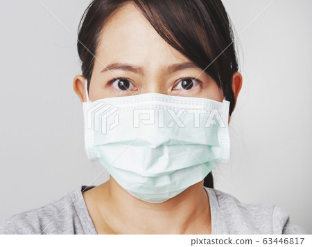 Asian woman was cold and sick, she wear green mask to prevent the virus covid. How to wear and pull mask from face. Covid 19 spread from Chinese people in Wuhan city. Close up face and eyes. Asian woman was cold and sick, she wear green mask to prevent the virus covid. How to wear and pull mask from face. Covid 19 spread from Chinese people in Wuhan city. Close up face and eyes. 63446817