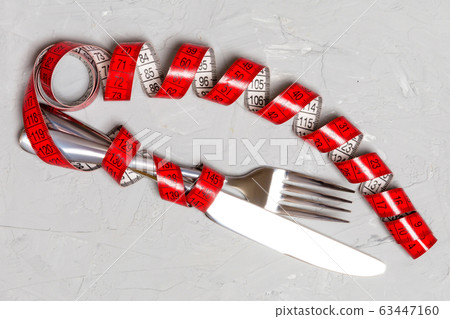 Diet concept with fork, knife and measuring tape Diet concept with fork, knife and measuring tape 63447160