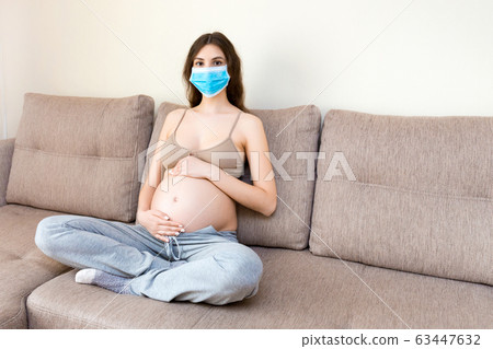 Young pregnant woman in protective medical mask  63447632