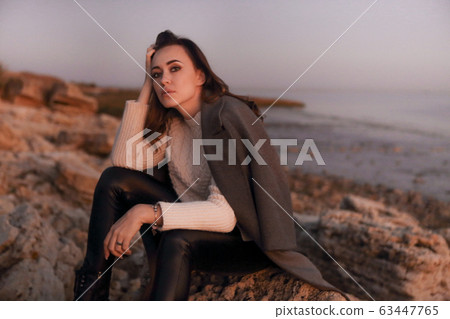 Young woman sitting on autumn beach 63447765