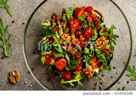Vegetable salad with arugula, tomatoes, avocado, splashed with balsamic sauce in a glass bowl. Top view. 63448399