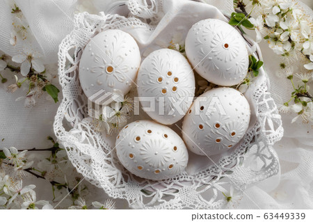 White Easter eggs decorated with wax and drilled holes 63449339