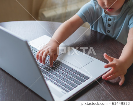 Child explores silver metal laptop. Curious toddler boy presses buttons. Child explores silver metal laptop. Curious toddler boy presses buttons. 63449853