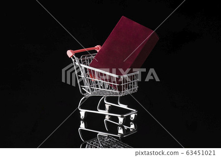 Shopping trolley cart and fragrance box on black background. Buying presents concept, online 63451021