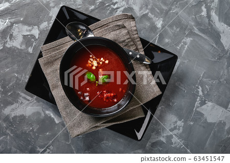 Tomato soup in a black bowl on a gray stone background. View from above. Copy space. Gray background. calm light. Food concept 63451547