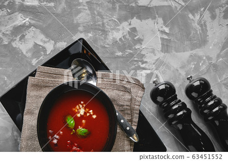 Tomato soup in a black bowl on a gray stone background. View from above. Copy space. Gray background. calm light. Food concept 63451552