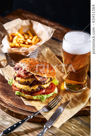 Delicious hot spicy black burger with chili pepper and glass of beer on cutting board on white wood table 63451564