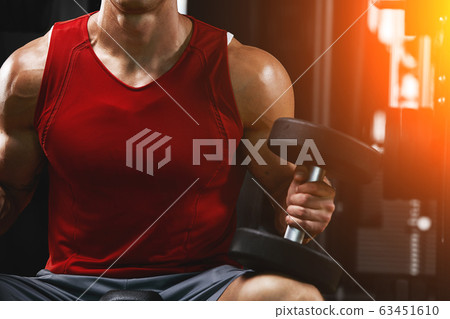 A shirtless muscular man is doing biceps exercises with dumbbell exercises as part of his bodybuilding workout. Fitness motivation, sports lifestyle, health, athletic body, body positive. Film grain A shirtless muscular man is doing biceps exercises with dumbbell exercises as part of his bodybuilding workout. Fitness motivation, sports lifestyle, health, athletic body, body positive. Film grain 63451610