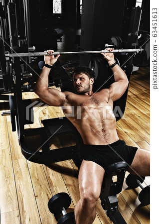 handsome young man doing bench press workout in gym, Fitness motivation, sports lifestyle, health, athletic body, body positive. Film grain, selective focus handsome young man doing bench press workout in gym, Fitness motivation, sports lifestyle, health, athletic body, body positive. Film grain, selective focus 63451613