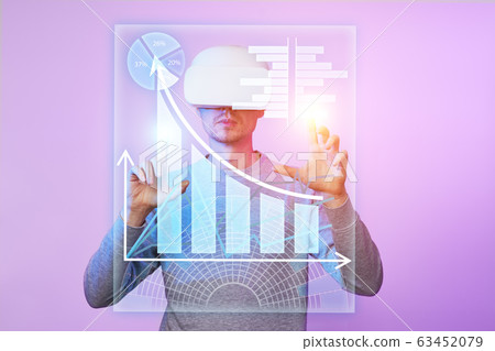 Man uses a virtual reality headset to work with data in the form of graphs and charts. 63452079