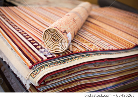 Stack of multicolored quality rugs at carpet shop Stack of multicolored quality rugs at carpet shop 63456265