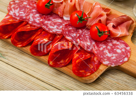 Spanish tapas - slicing sausages and jamon served on wooden board Spanish tapas - slicing sausages and jamon served on wooden board 63456338