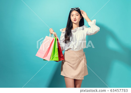 Young smiling asian woman holding multi coloured shopping bags and hands touch the glasses. 63457783