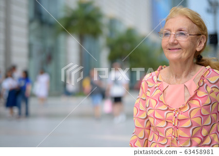 Beautiful senior tourist woman with blond hair relaxing around t 63458981