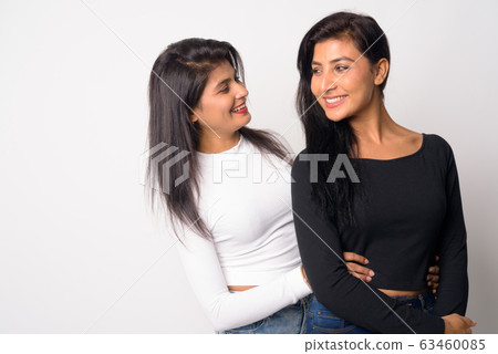Two happy young beautiful Persian women embracing and looking at each other Two happy young beautiful Persian women embracing and looking at each other 63460085