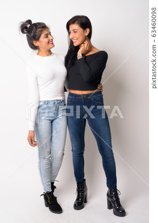 Full body shot of two happy young Persian women smiling and looking at each other Full body shot of two happy young Persian women smiling and looking at each other 63460098