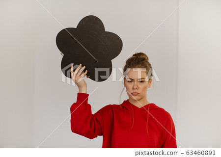 A teenager girl is holding a chalk board in the shape of a thought bubble. 63460891